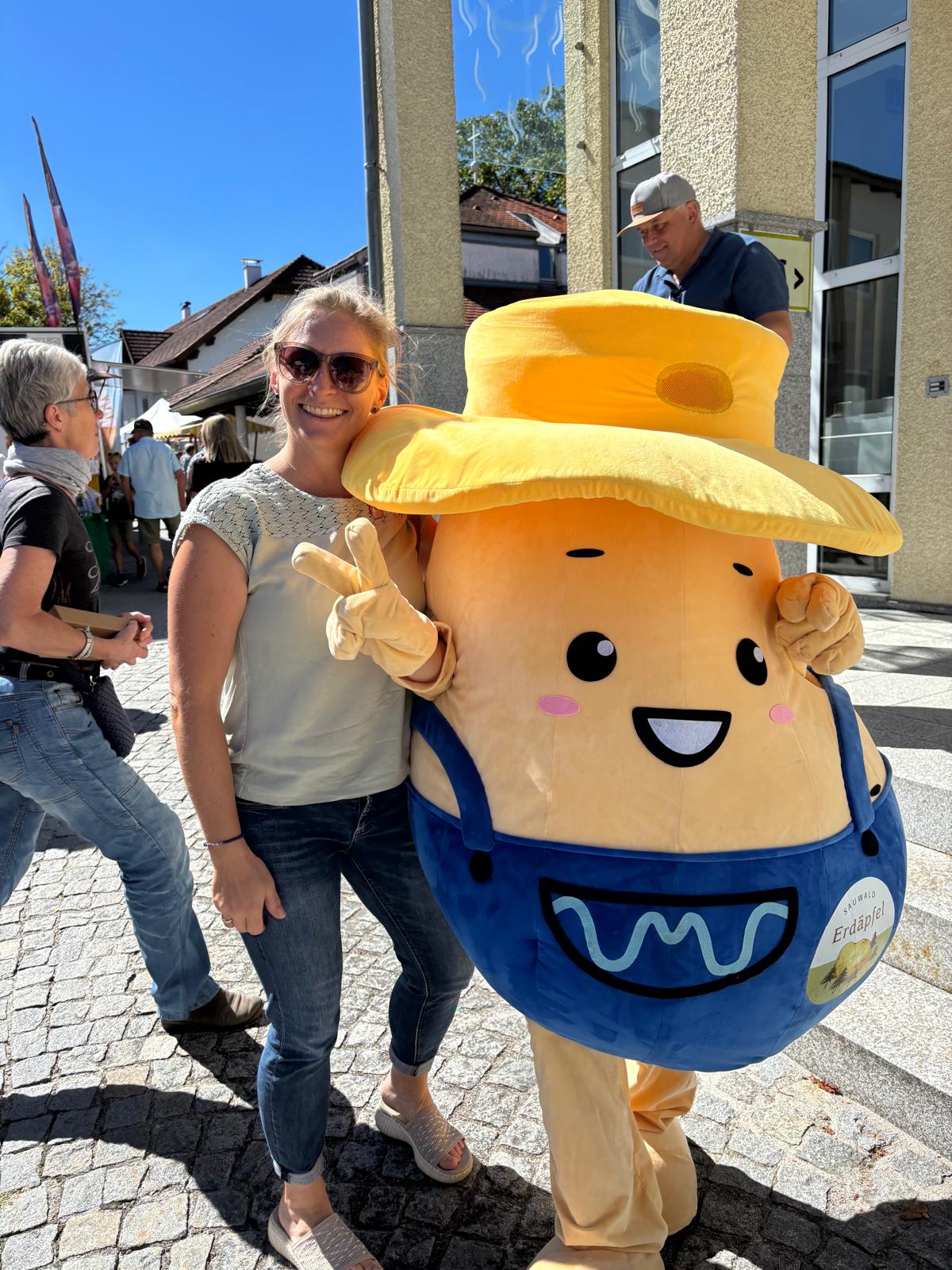 Erdäpfel-Maskottchen mit lächelnder Frau bei einem Fest in der Südsteiermark