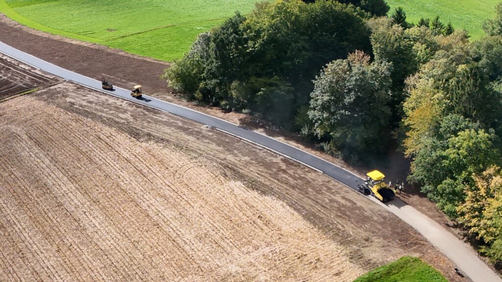 Detailausschnitt: Asphaltfertiger und zwei Walzen auf der frisch asphaltierten Fahrbahn des Agrarweges Reiting-Kiriau