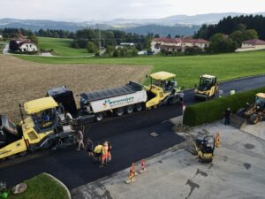 Asphaltierungsarbeiten in Österreich mit Baumaschinen und Arbeitern auf einer Landstraße